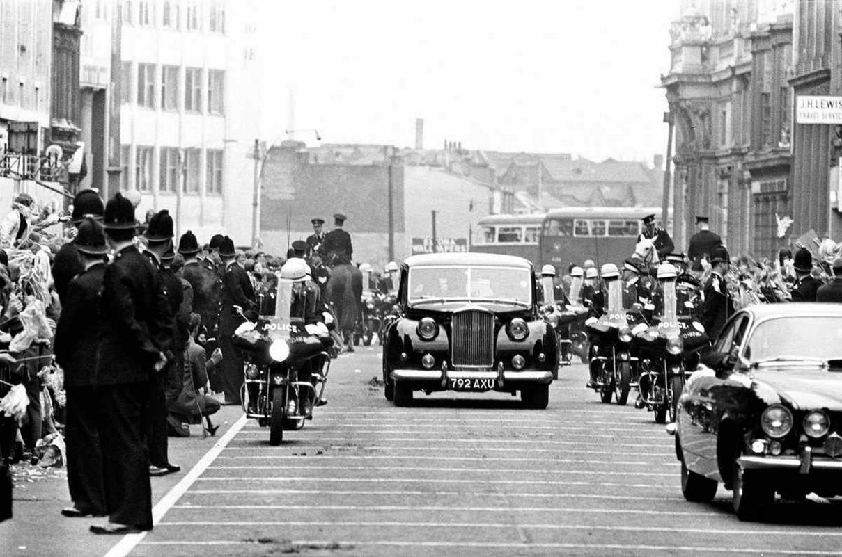 Premiere of "A Hard Day's Night", crowds gather to catch sight of The Beatles before the Northern premiere starts in Liverpool. The Beatles arrive in a car with a line of police escorts 10th July 1964